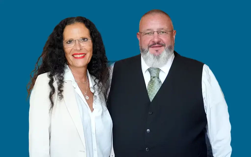 Foto von Rechtsanwältin Anja Mack und Rechtsanwalt Tino Brückner vor blauem Hintergrund